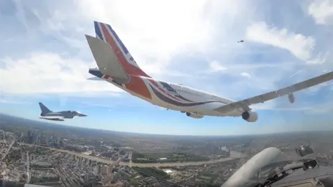 An image taken from a plane, showing two other planes flying alongside it as part of the King's Birthday Flypast.