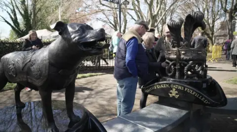 A statue of a dog is on the left and a memorial on the right includes a crown and the words oaths taken, oaths fulfilled.