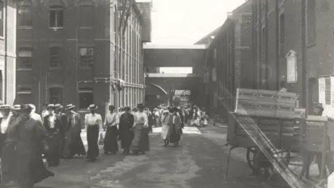 UNILEVER A black and white photograph of Colman's workers leaving work to go home in about 1910.