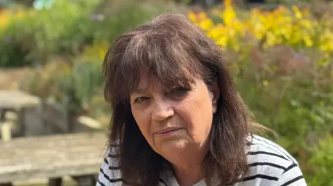 George King/BBC A head shot of Jenny Kirtley. She has thick long brown hair. She is wearing a striped top and looking directly into the camera.