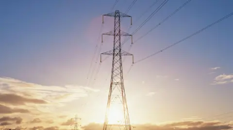 Power pylons stand out against a sunny and cloudy sky