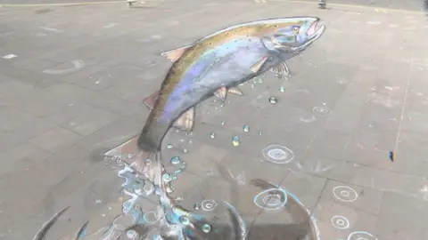 BBC A large chalk salmon drawn on the pavement.