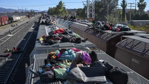 Reuters Migranten rusten uit in treinwagons terwijl ze wachten op een goederentrein die naar de Amerikaanse grens rijdt