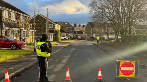 Rob Smith/BBC A police cordon in place on a residential street