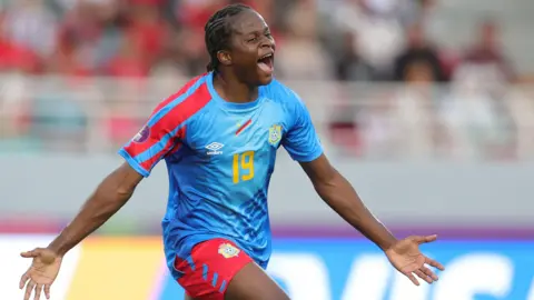 Merveille Kanjinga closes her eyes, spreads her arms and screams as she runs to celebrate a goal for DR Congo at the Women's Africa Cup of Nations in Morocco