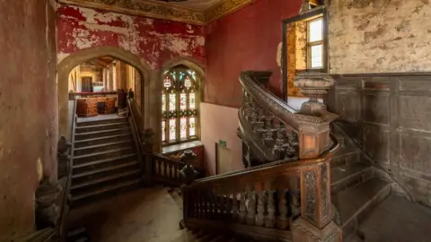 BHBT Two flights of wooden stairs with red peeling walls