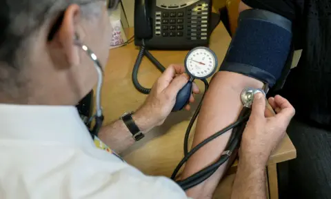 PA GP checking someone's blood pressure