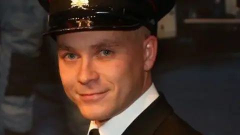 Shropshire Fire and Rescue Service A man in a dark suit and dark military-style cap