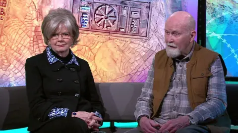 Barbie Reynolds and Peter Reynolds sitting on a sofa in the BBC Newsnight studio 