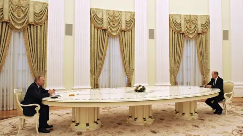 Kremlin Press Office/Anadolu Agency via Getty Images Putin and Scholz sat opposite each other at a very long table