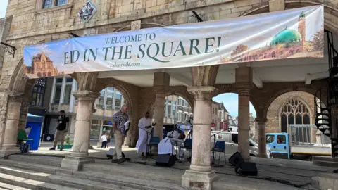 Jenny Kirk/BBC A large banner which reads Welcome to Eid in the Square attached to the bottom of what looks like an old building.