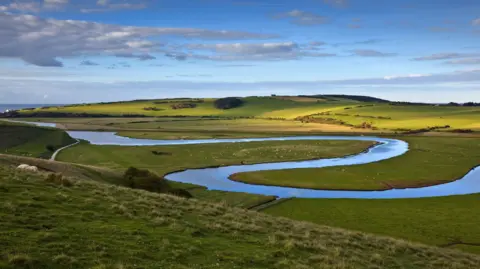 Getty Images A meandering river within a sweeping green landscape. It looks picturesque. 