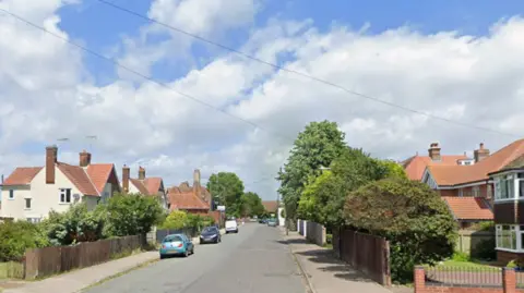 Google A general view of Church Road in Felixstowe. The road is lined by houses with red roofs. Some cars are parked on the left hand side of the road. 