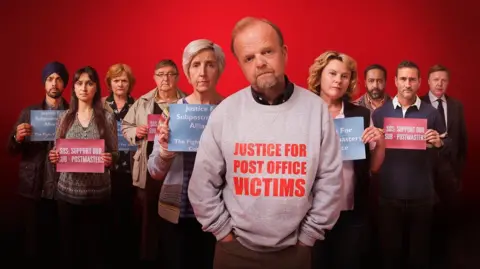 ITV The cast of Mr Bates vs The Post Office. Actor Toby Jones, centre, wears a grey sweatshirt with the words Justice For Post Office Victims on it in red.