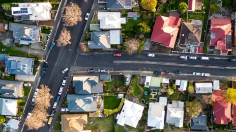 An aerial view of leafy streets and houses with different coloured roofs