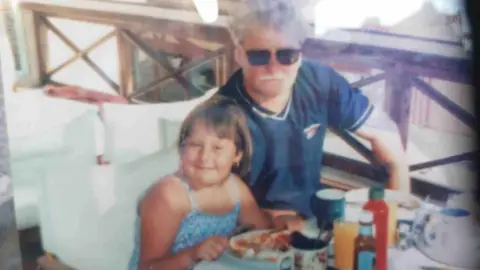 Suzanne Wiggins A young girl, Courtenay and her father, David posed for a photo whilst having dinner. They appear to be on an abroad holiday. 