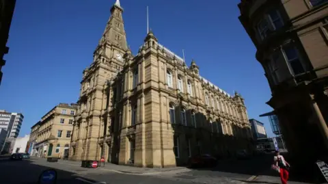 LDRS A large stone built building has a clock tower and large arched windows