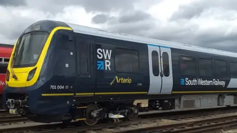 A stationary South Western Railway train, painted in the company's blue, white and yellow livery.