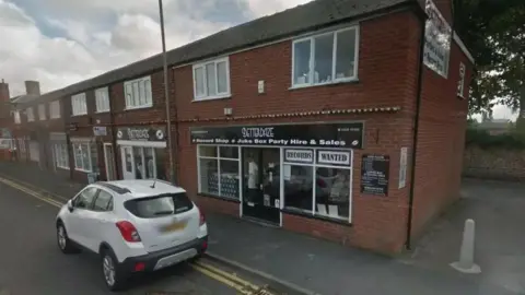 Google The Betterdaze record shop in Northallerton, a red brick two storey building with a black and white sign and a white car outside 