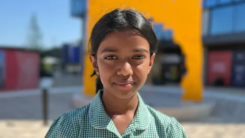 Thivigka is wearing a green and white chequered school uniform