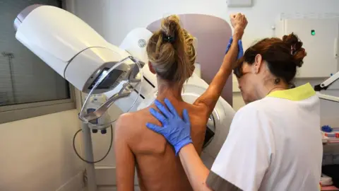 Female health care worker assisting woman getting a mammogram 