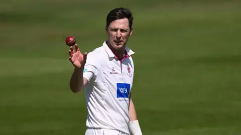 Matt Henry catching the ball as he prepares to bowl