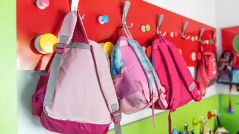 Getty Images Pink school bags hanging from hooks inside a bright room in a school