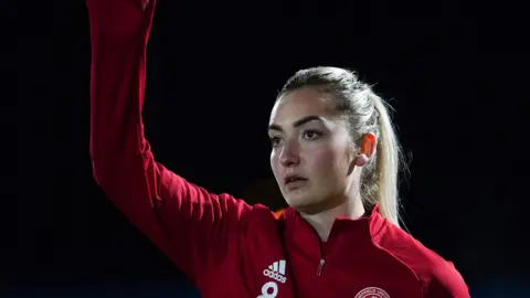 Maddy Cusack in a red Sheffield United jacket with her arm in the air