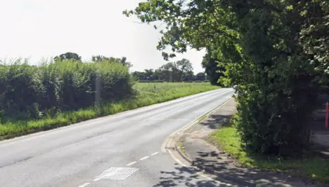 Google Maps A Google Maps street view image of Brightwell Road. It is empty but a car appears to be travelling on it from the distance. On the left of the image - and the road - there are green bushes, and on the right, there is a tree with green leaves.