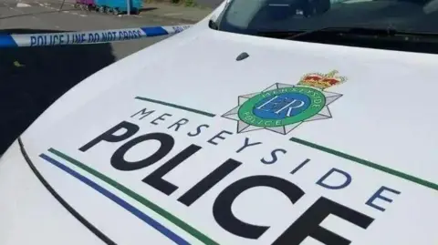 The bonnet of a Merseyside Police patrol car, with the force's badge and name painted onto a white background