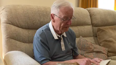 Peter Herke holds the photo album his mother put together as he was growing up in German occupied Poland.