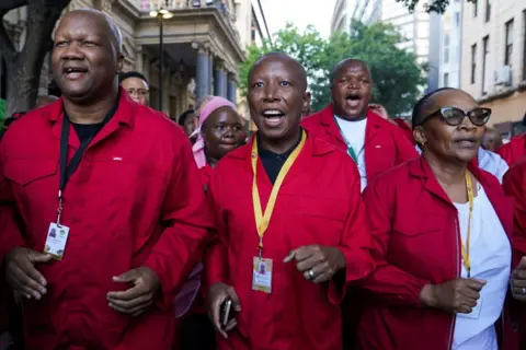 Nic Bothma / Reuters Julius Malema memimpin anggota pejuang kebebasan ekonominya ke pidato negara bagian, mengenakan overall merah merek dagang mereka.