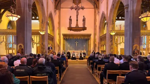 Liverpool City Council Church interior showing members if the emergency service in the congregation