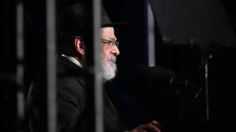 EPA Rabbi Yehoram Ulman, the father-in-law of Rabbi Eli Schlanger, one of the prominent victims of the Bondi Beach Massacre, addresses people during the National Day of Reflection vigil and commemoration for the victims and survivors of the Bondi Massacre at Bondi Beach 