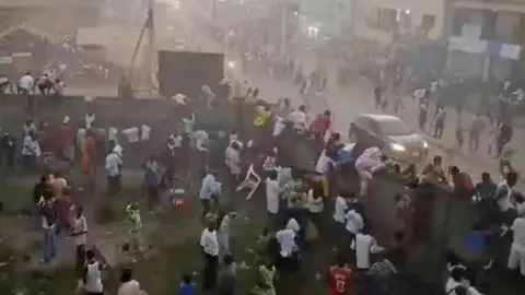 Reuters A screengrab shows many people in a football stadium in Nzerekore, Guinea, scrambling to leave with some climbing on stadium wall.