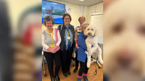 Marie Curie Four women volunteers pose for a picture, with one of them holding up a white dog