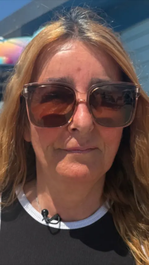 A woman with blonde hair wearing a black top and wearing sunglasses.