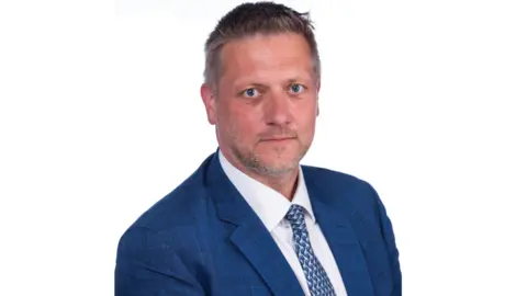 Buckinghamshire Council Steven Broadbent is wearing a blue jacket, with a blue and silver tie and a white shirt underneath.