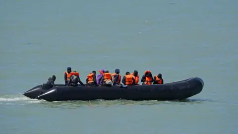 A large rubber rib boat with several men on board wearing orange life jackets out at sea.