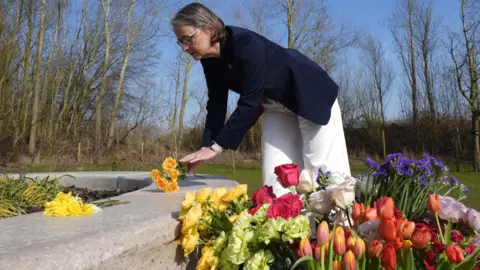 El director gerente de PA Media National Memorial Arboretum, Philippa Rawlinson, colocando flores en los árboles de la vida de la vida antes de una ceremonia que marca el quinto aniversario de la pandemia Covid-19 en el National Memorial Arboretum, en Trent Burton-on-Trent