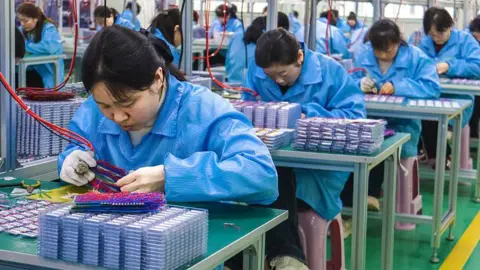 Women in blue coats work on an electronics production line in a factory in Nanyang, Henan Province of China.