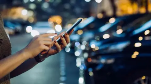 Getty Images Stock image of woman with phone in car park