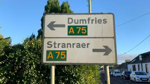 Road signs pointing to Stranraer in one direction and Stranraer in the other on the A75 route