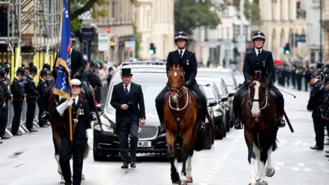 Getty Images Police officers on horses lead the funeral cortege for PC Andrew Harper as officers line the street