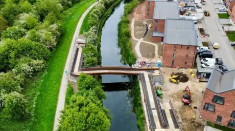 A bridge over a canal with houses on the right-hand side.