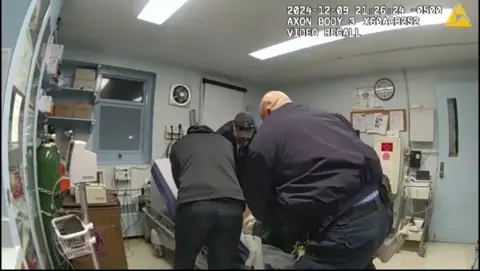 Screenshot of bodycam footage showing officers holding down Robert Brooks in a prison infirmary.