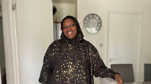 Suwaidu Sanyang smiles for a picture in her living room