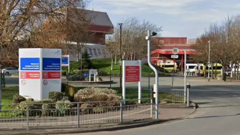 The entrance to Southport & Formby District Hospital showing an red brick building and a number of ambulances parked outside