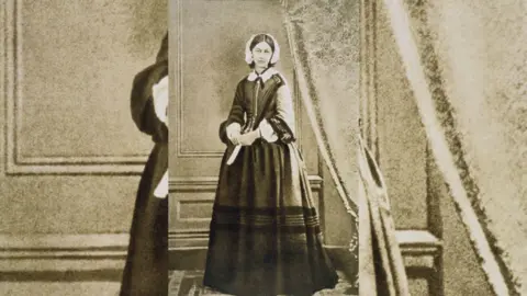 Old portrait of Florence Nightingale wearing a long black dress and a white head scarf.