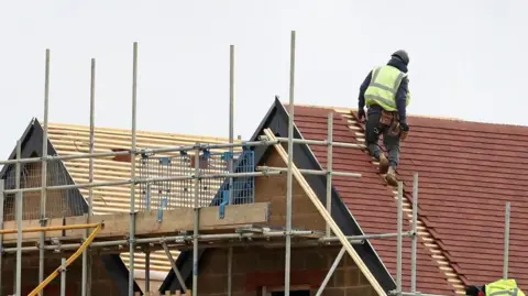 Stock image of a builder working on a tiled roof